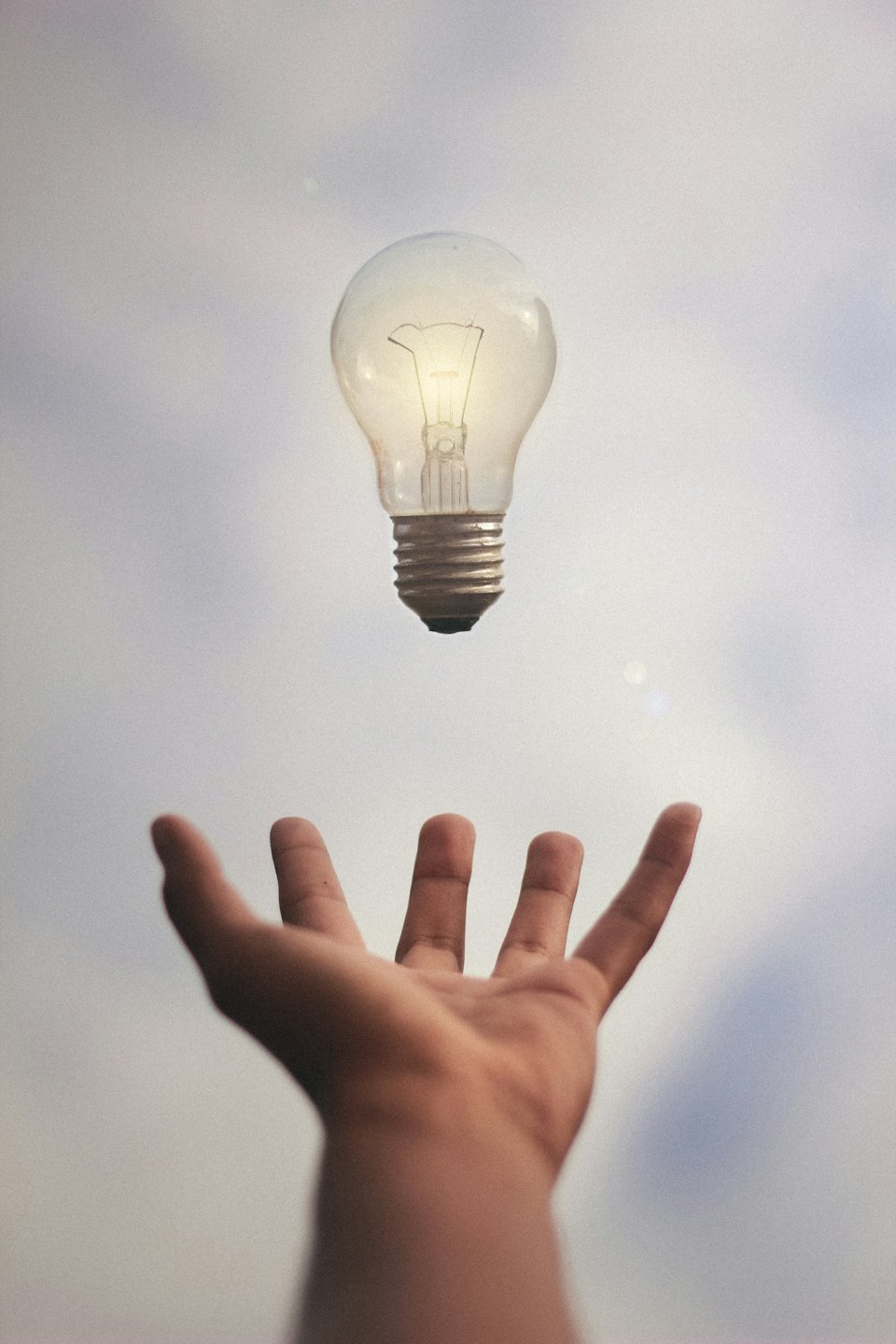 Human hand holding a glowing light bulb, symbolizing innovation.